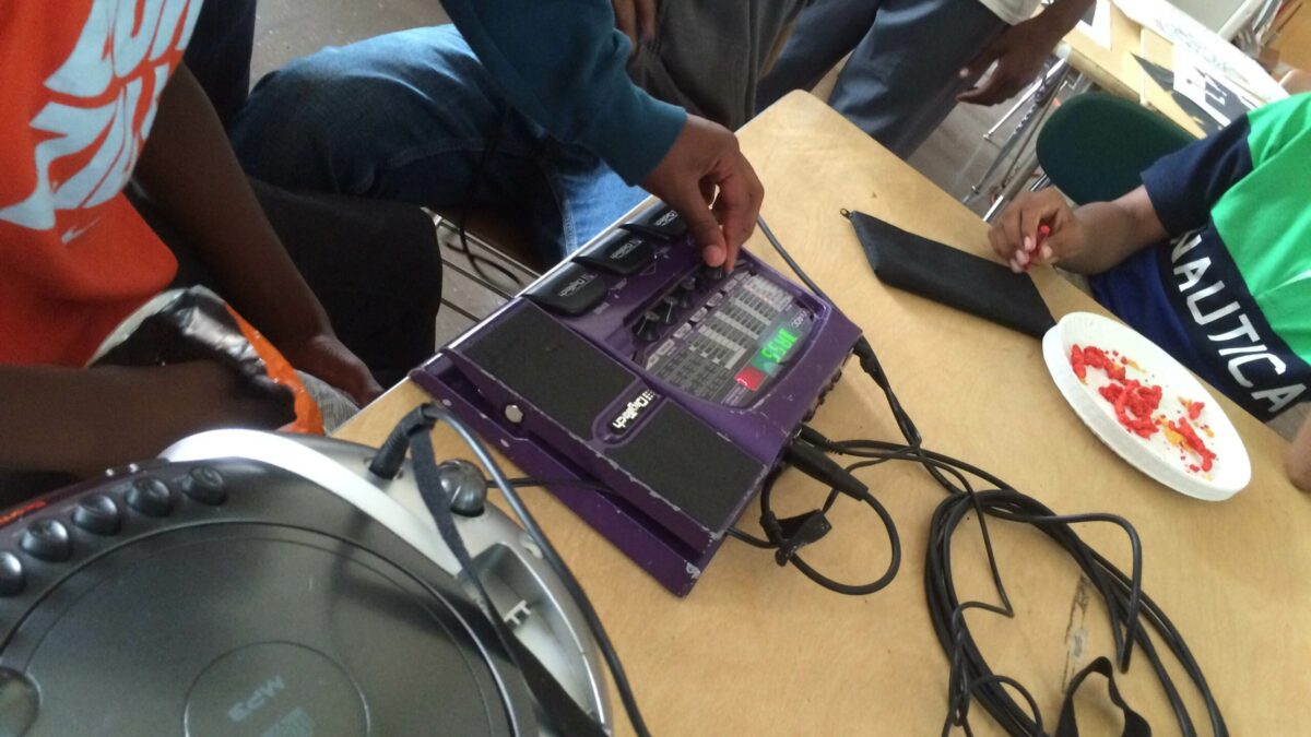 Four youth interacting with a portable mixer on a classroom desk