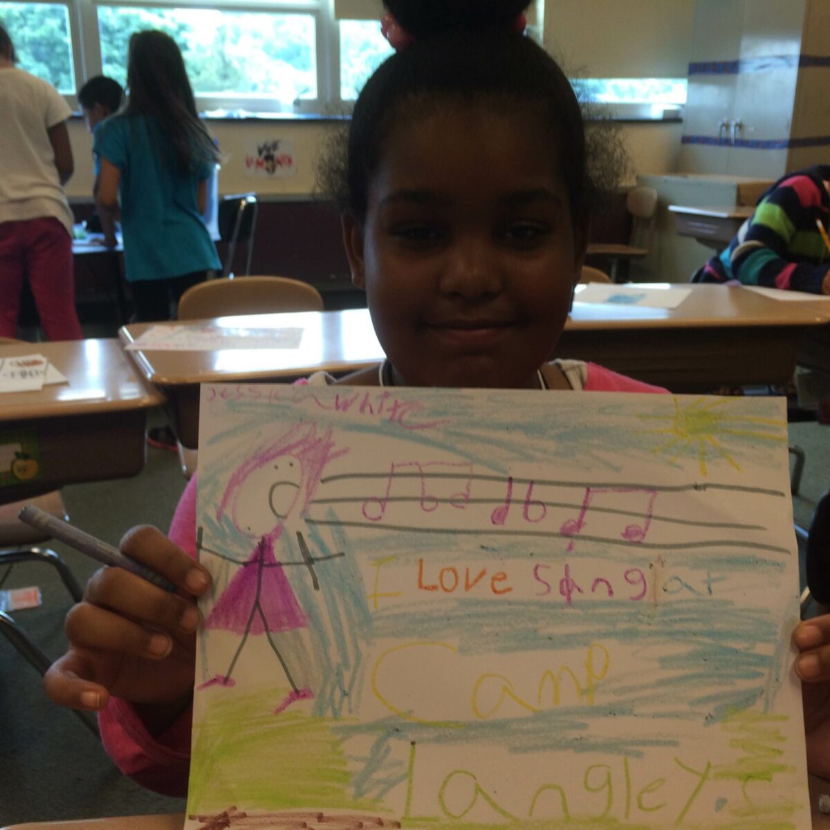 A youth holding up a drawing in a classroom