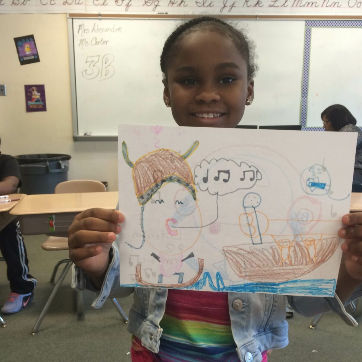 A youth holding up a drawing in a classroom