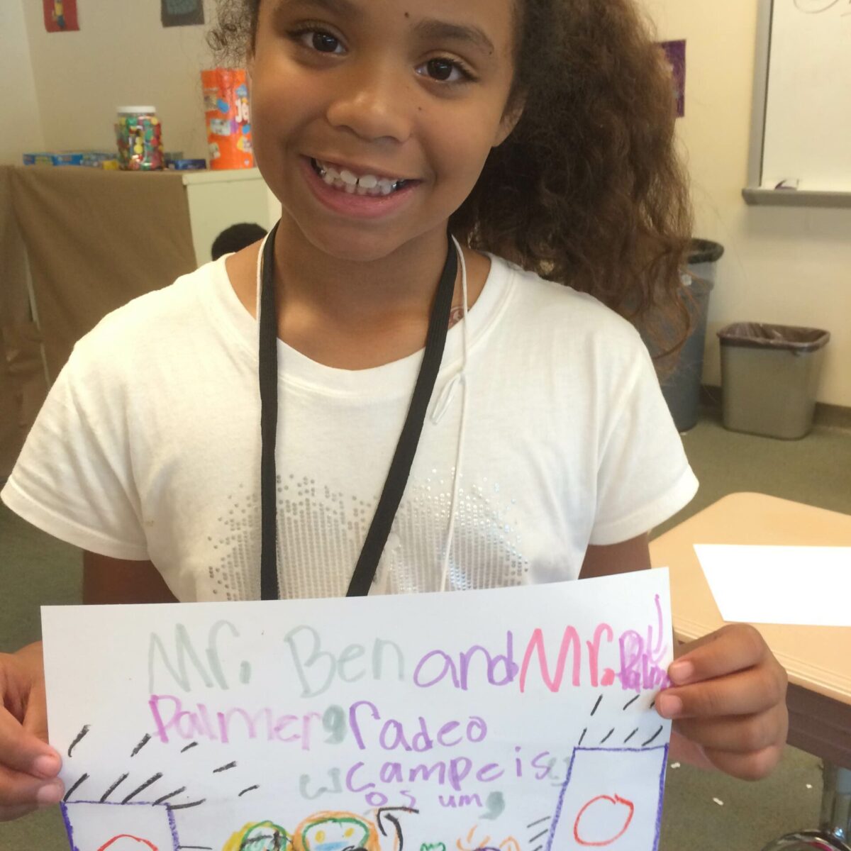 A youth holding up a drawing in a classroom
