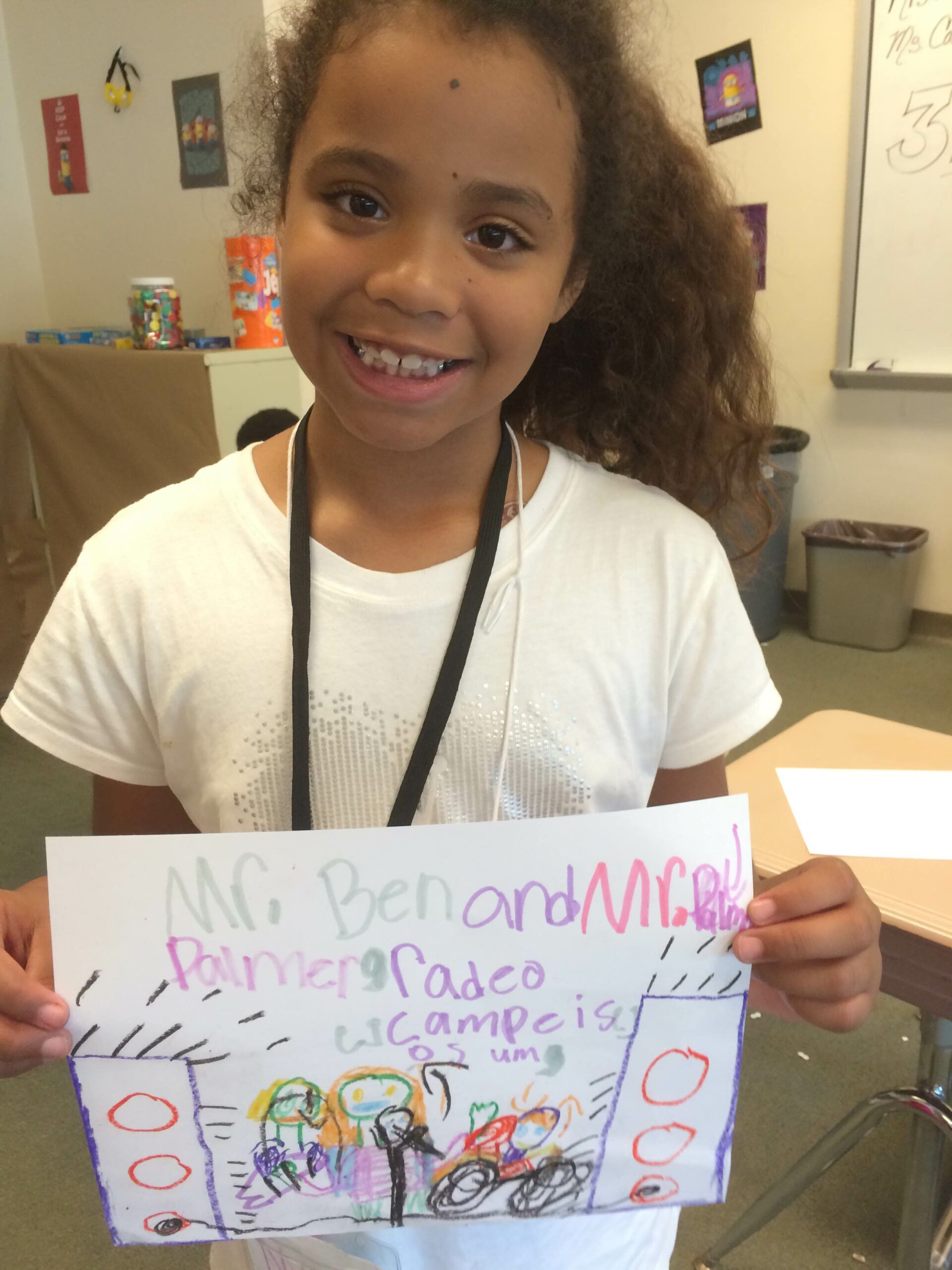 A youth holding up a drawing in a classroom