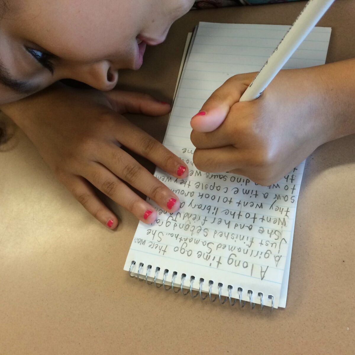 A youth writing onto a notepad on a classroom desk