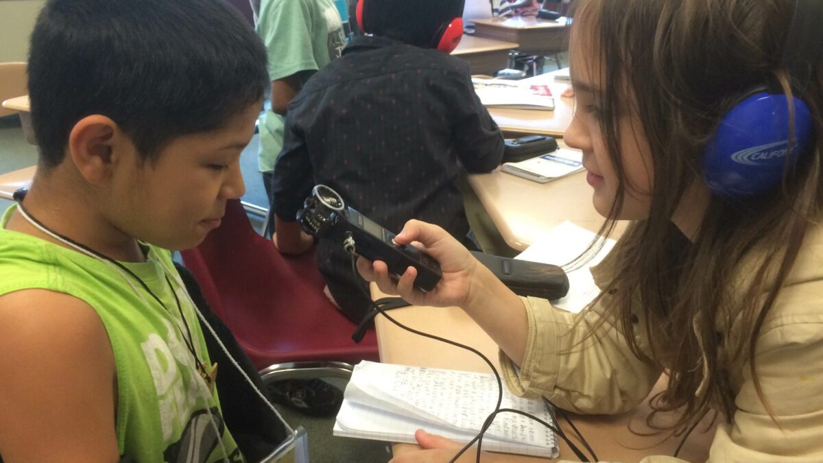 IMG_1389 A youth wearing headphones interviewing another youth with a portable recorder
