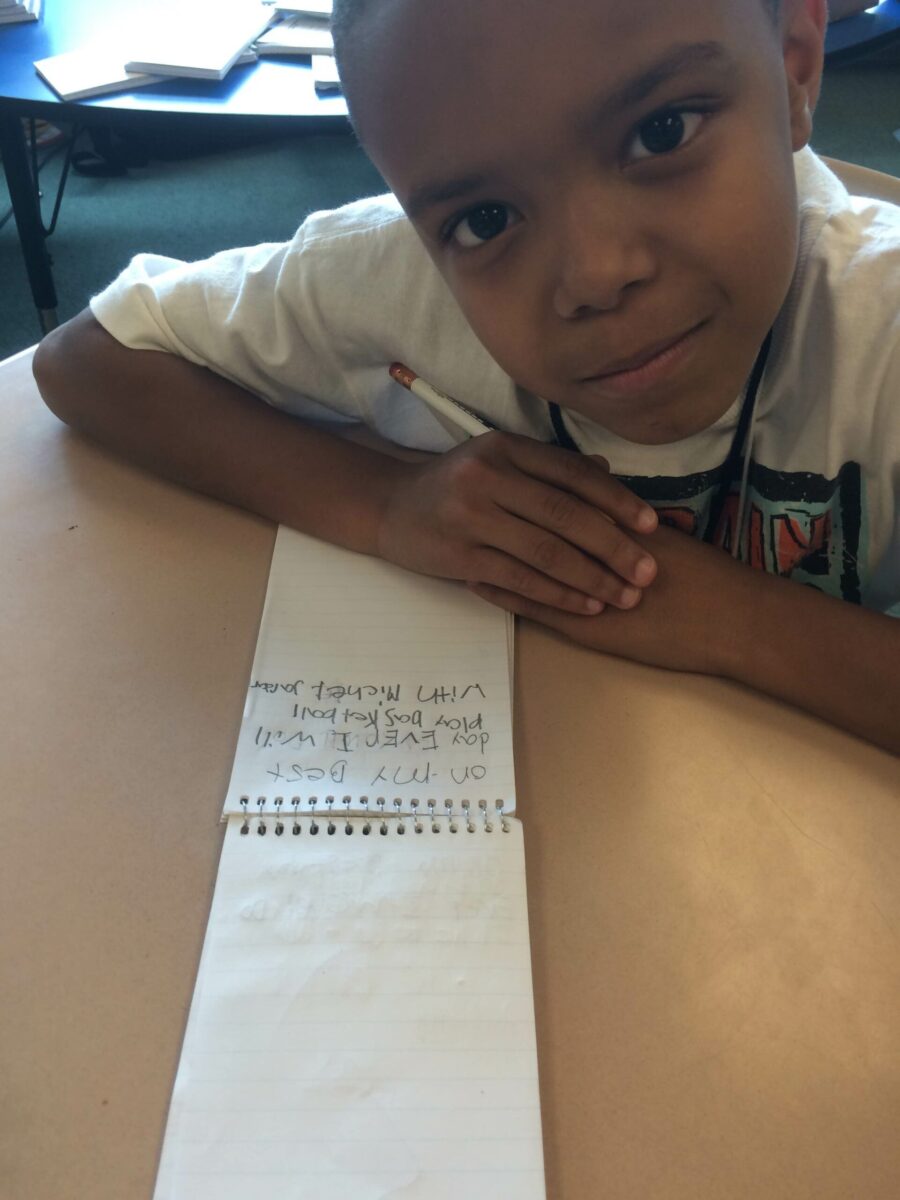 A youth sitting behind a notepad on a classroom desk