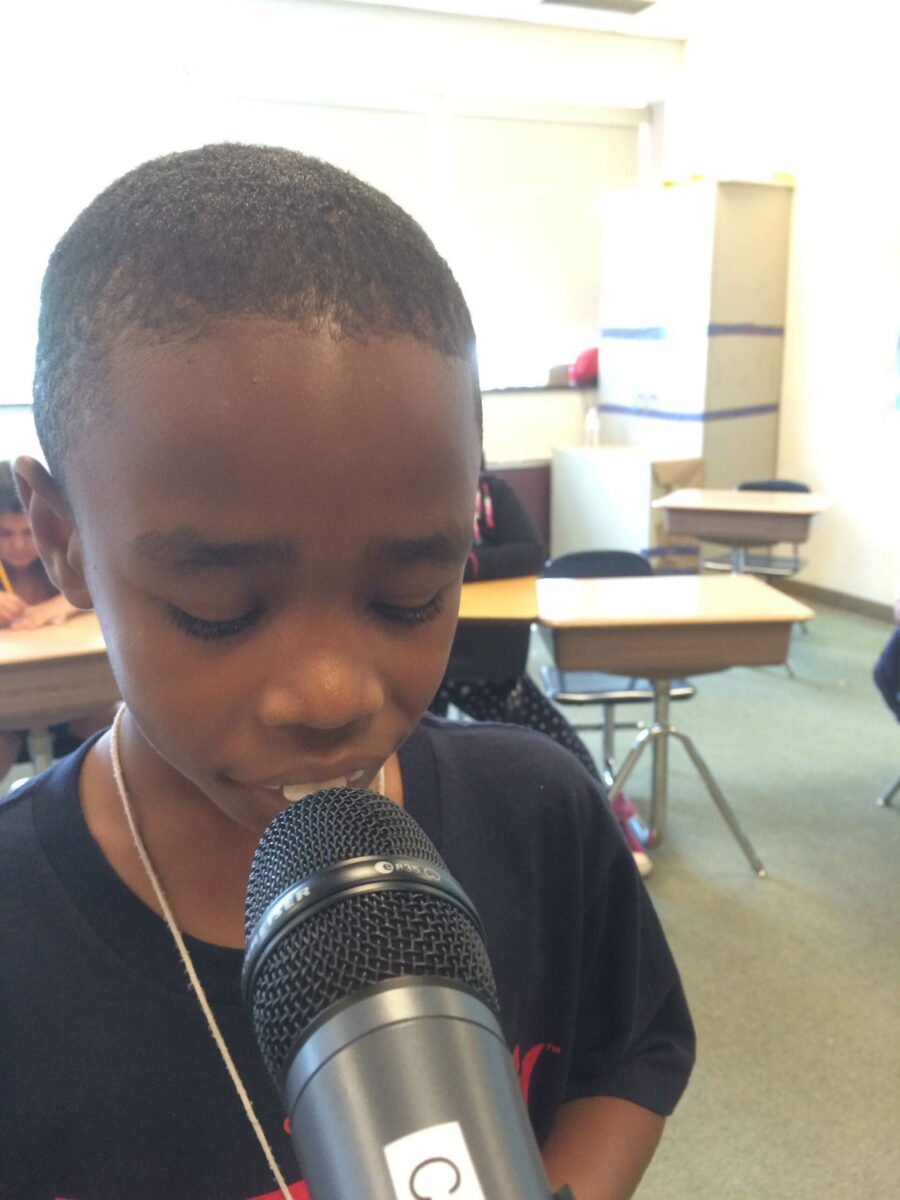 A youth speaking into a microphone in a classroom
