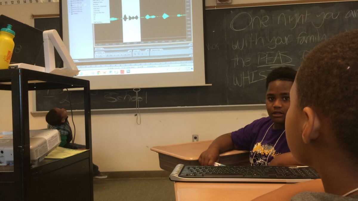 IMG_1475 Two youth looking at audio editing software on a projected screen in front of a blackboard in a classroom