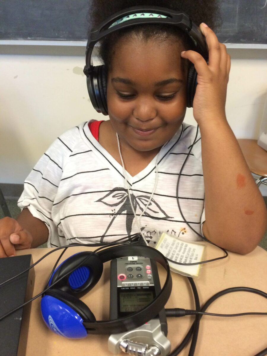 IMG_1512 A youth wearing headphones looking down at a portable recorder in a classroom