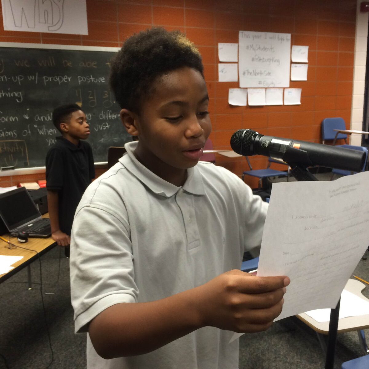 IMG_1725 A youth reading a piece of paper into a microphone in a classroom