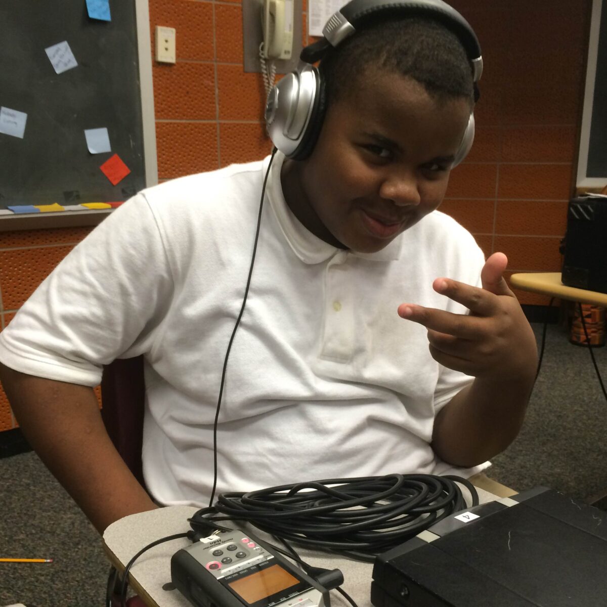 IMG_1727 A youth wearing headphones sitting and posing behind a portable recorder on a classroom desk