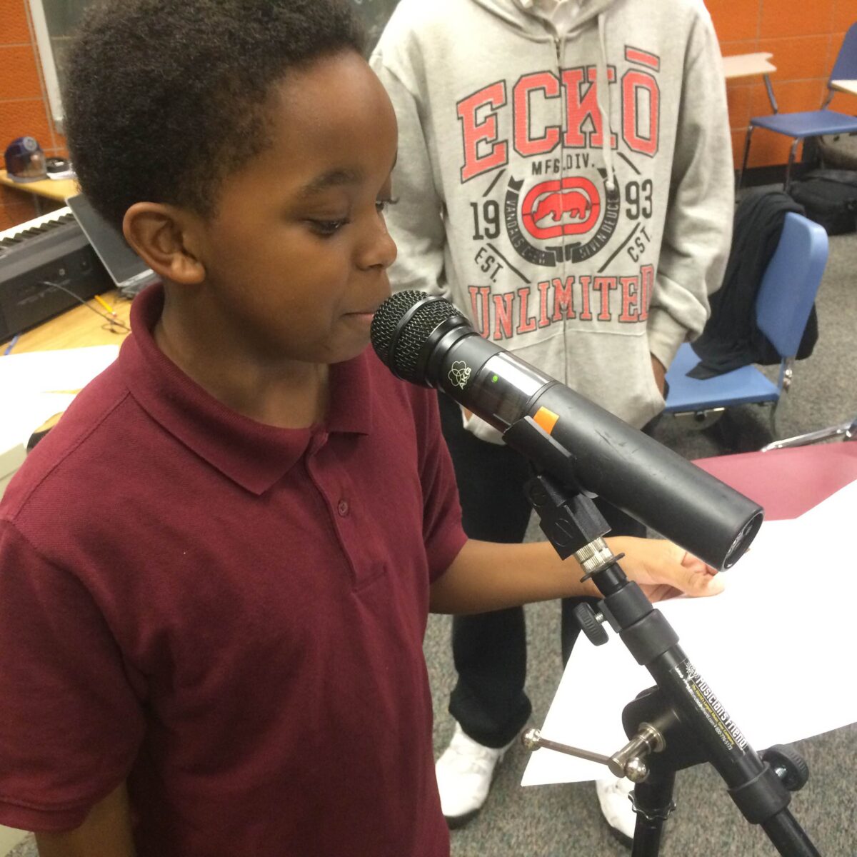 IMG_1730 A youth reading a piece of paper into a microphone in a classroom