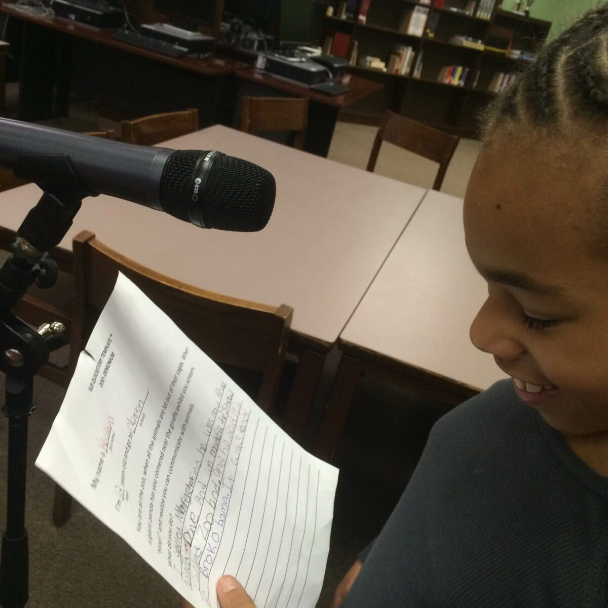 IMG_1873 A youth looking down at a piece of paper standing behind a microphone in a library