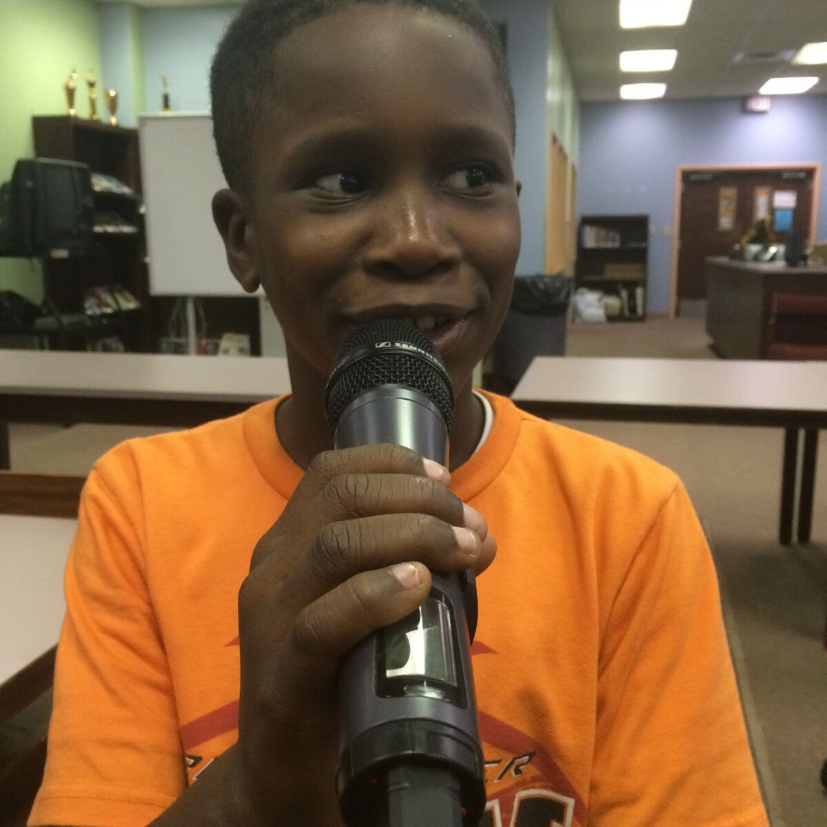 IMG_1878 A youth holding and speaking into a microphone in a library