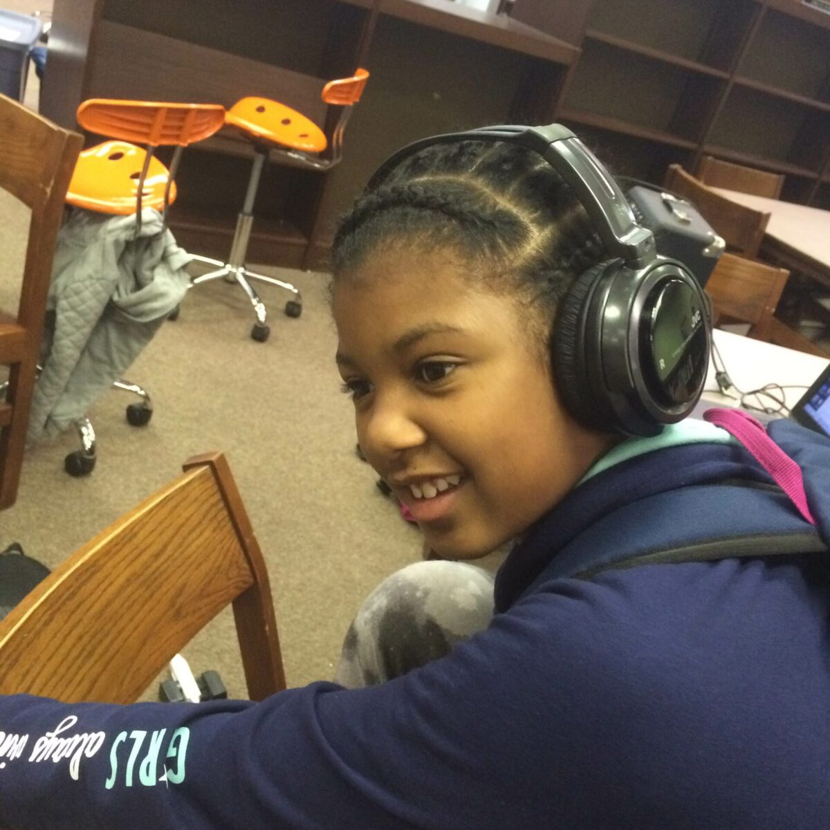IMG_1882 A youth wearing headphones sitting on a wooden chair in a library