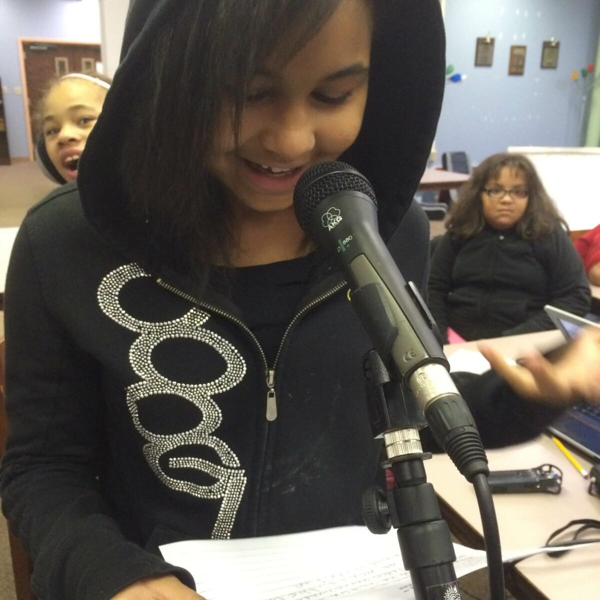 IMG_1909 A youth holding a piece of paper speaking into a microphone in a classroom