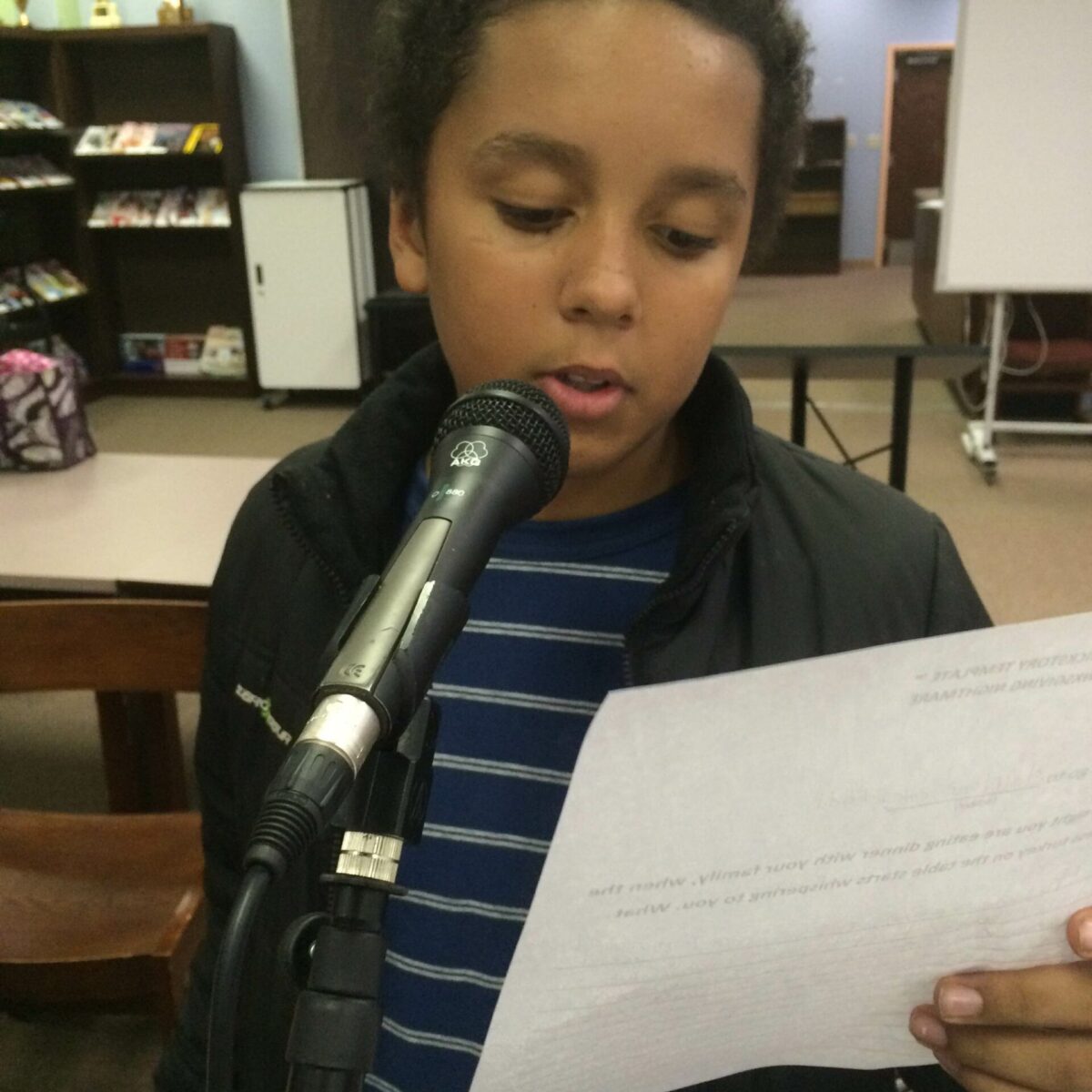 IMG_1915 A youth holding a piece of paper standing behind a microphone in a classroom