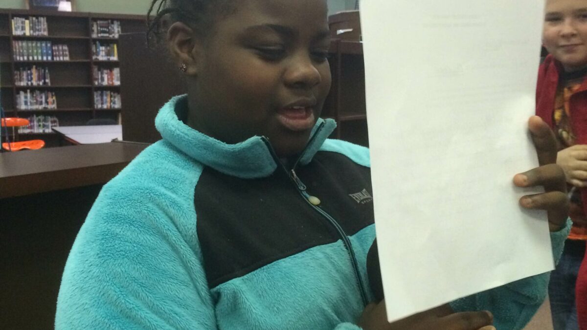 IMG_1989 A youth reading a piece of paper and holding a microphone in a library