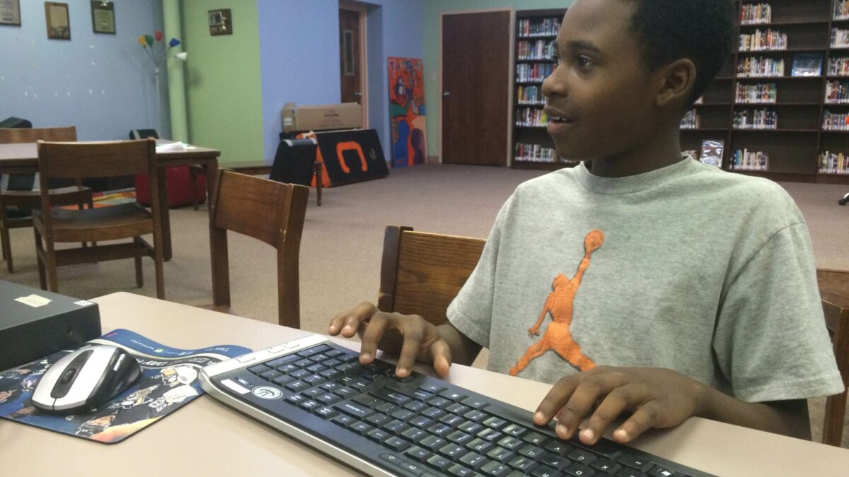IMG_2031 A youth typing on a keyboard sitting at a table in a library