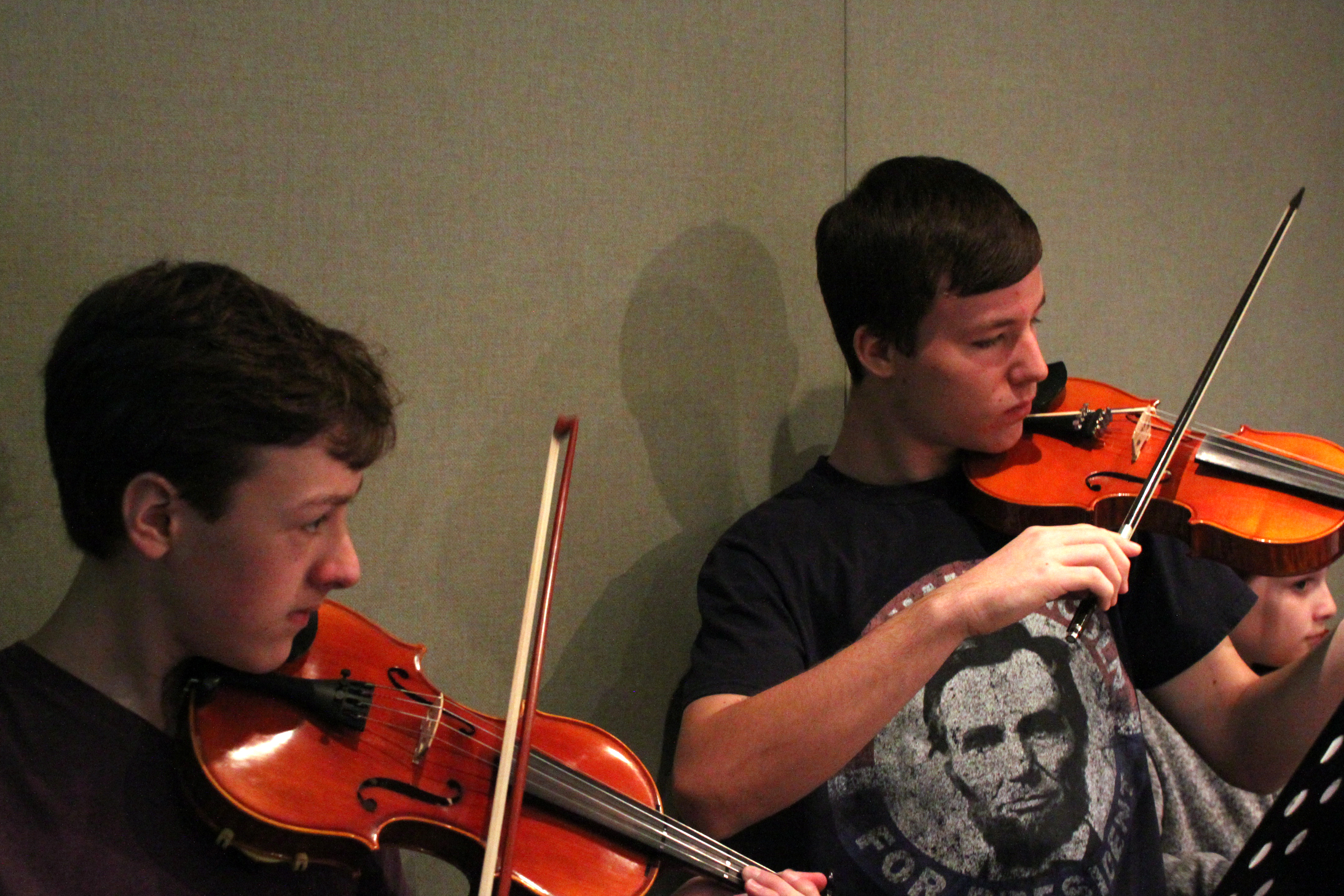 Two youth playing violins in a radio studio