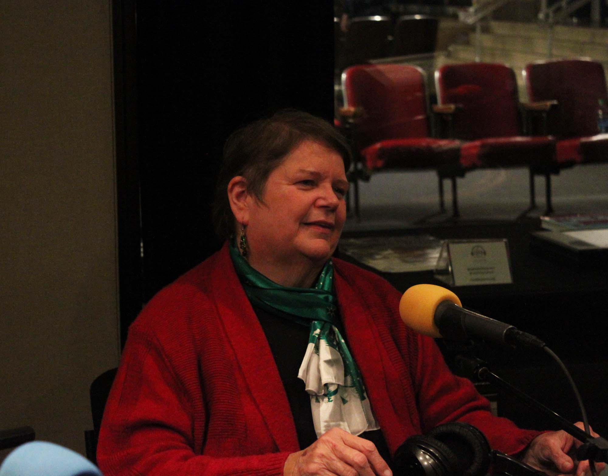 An adult speaking into a microphone in a radio studio