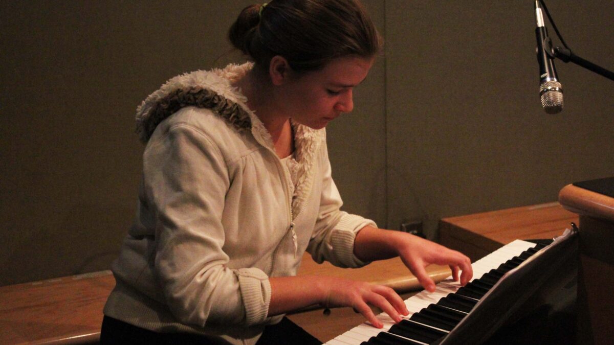 A youth playing a piano keyboard in a radio studio