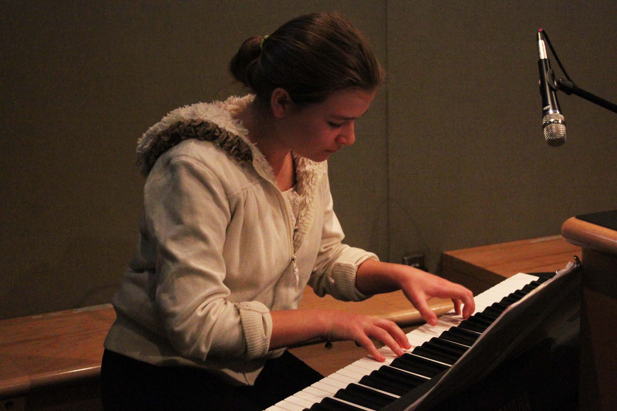 A youth playing a piano keyboard in a radio studio