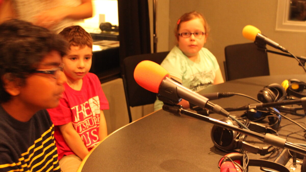 IMG_8809 Three youth sitting behind microphones in a radio studio