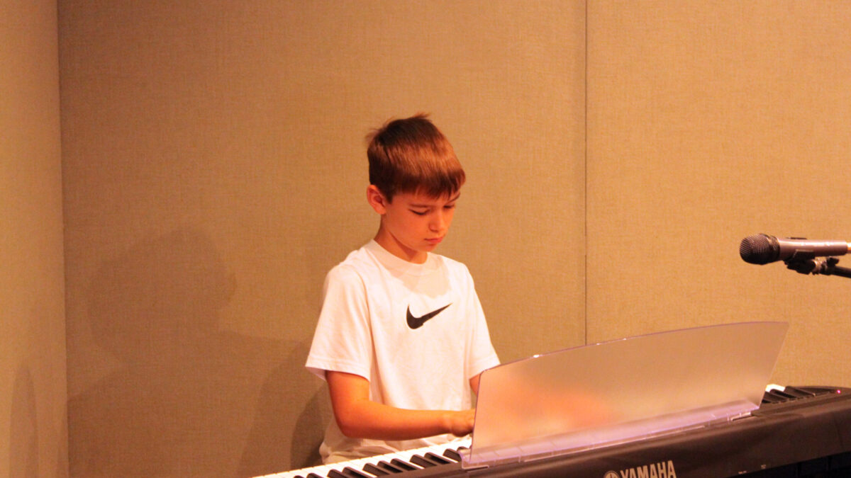 A youth playing a piano keyboard in a radio studio