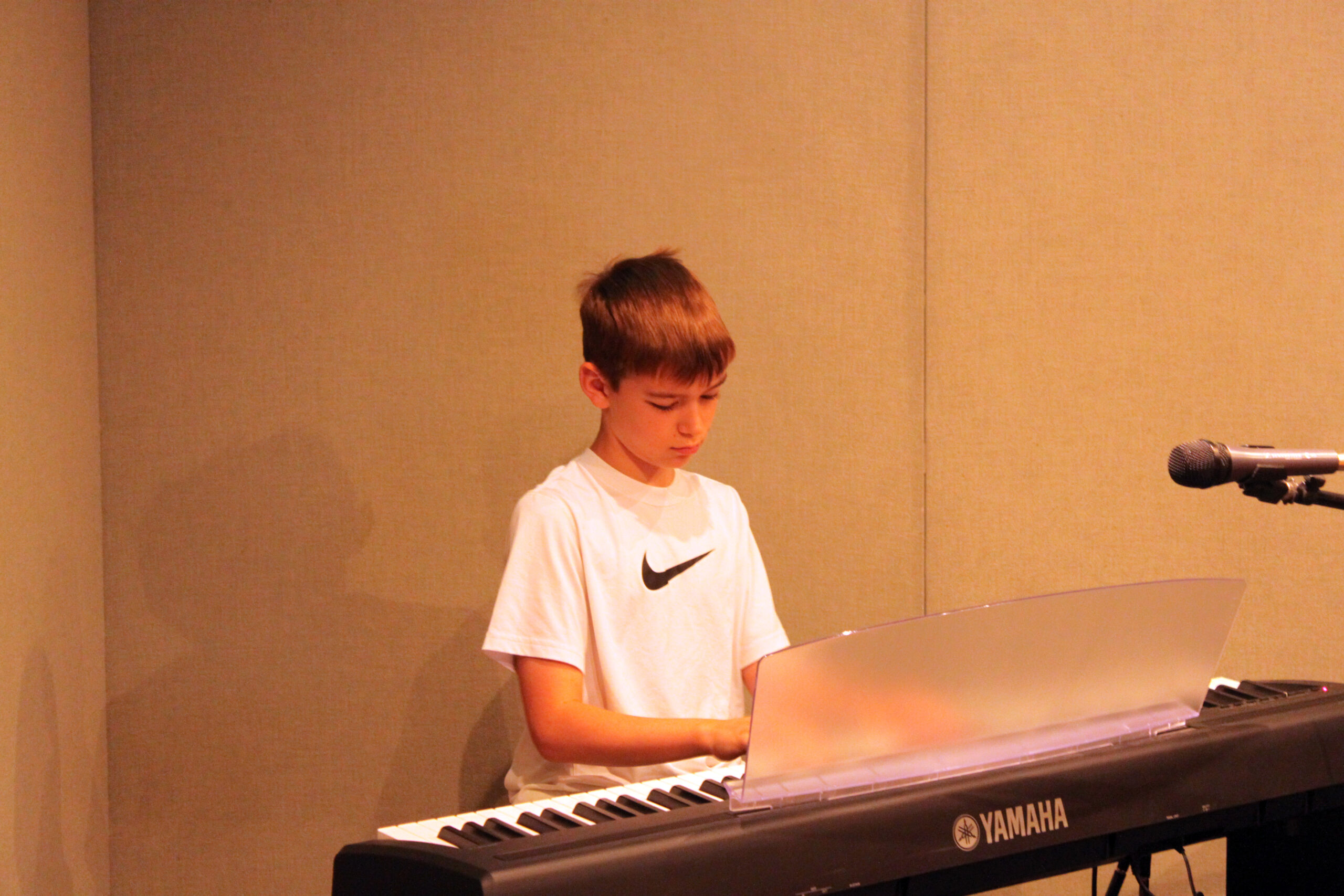 A youth playing a piano keyboard in a radio studio