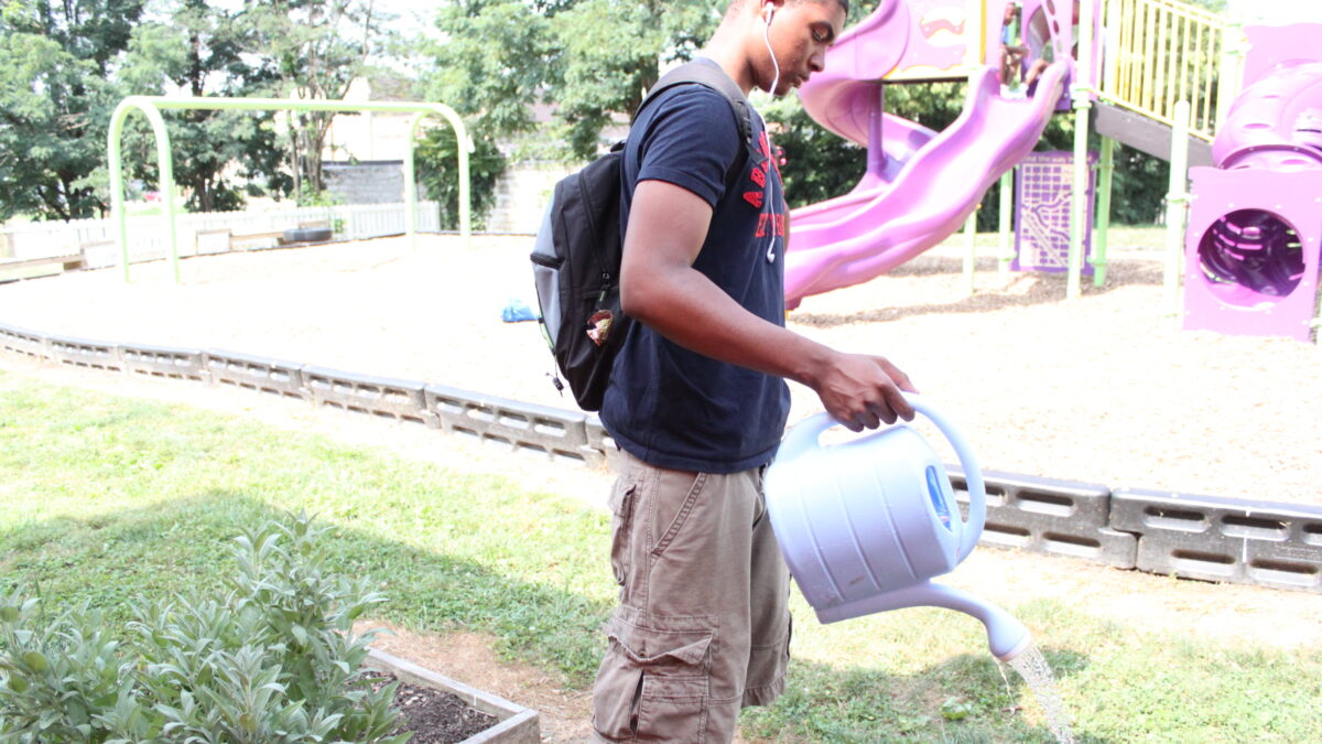 IMG_9716 A teen using a watering can in front of a playground