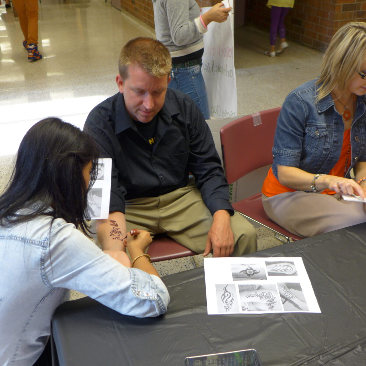 Three individuals looking down at pieces of paper on a black table