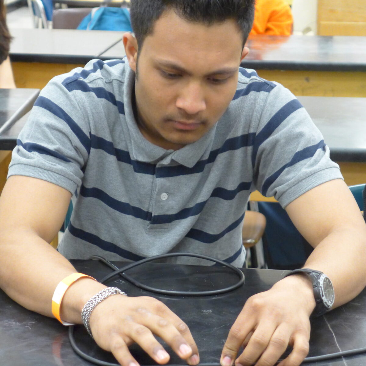 P1020634 A teen interacting with a wire on a classroom desk