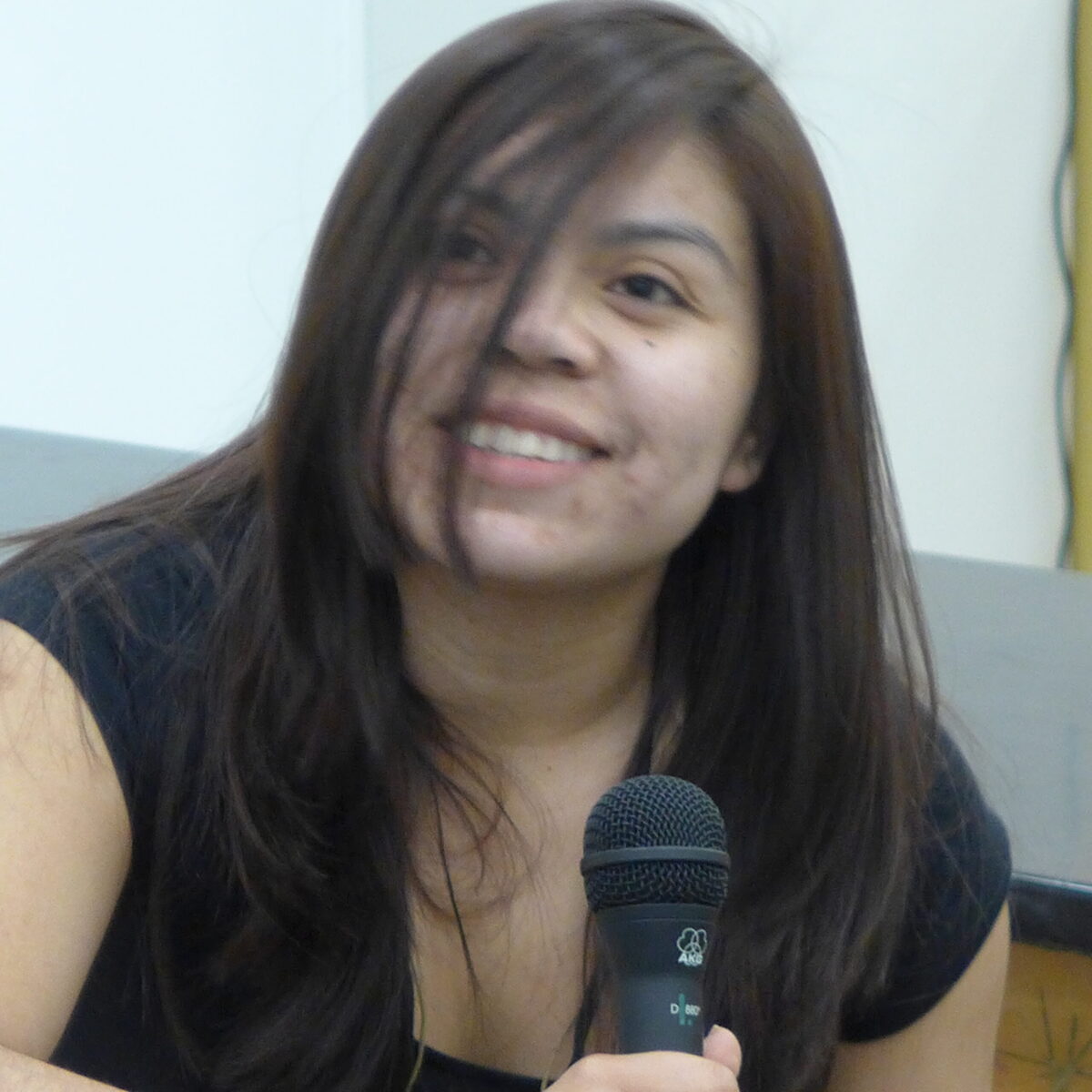 P1020636 A teen smiling while holding a microphone and sitting in a classroom
