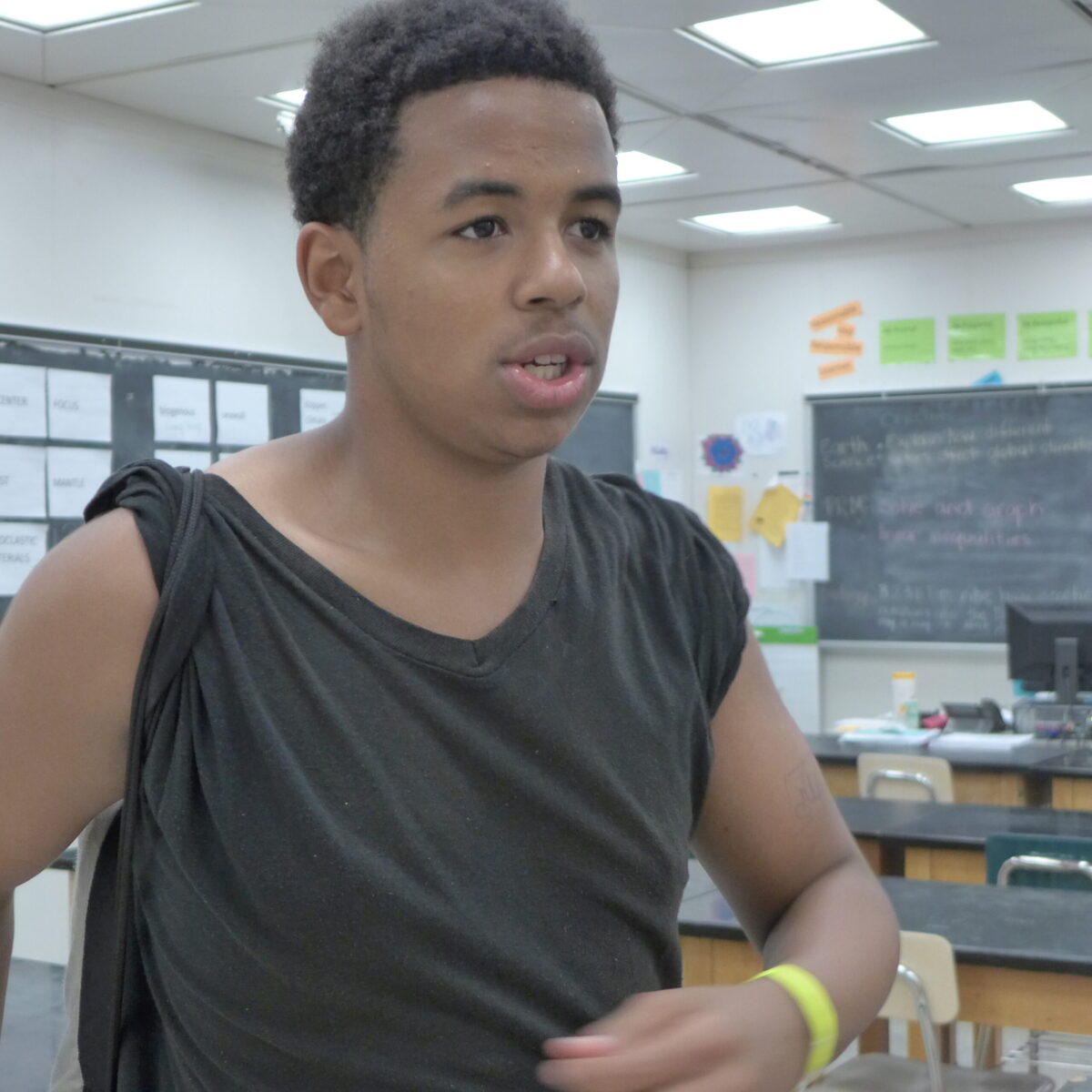 A teen looking to the right standing in a classroom