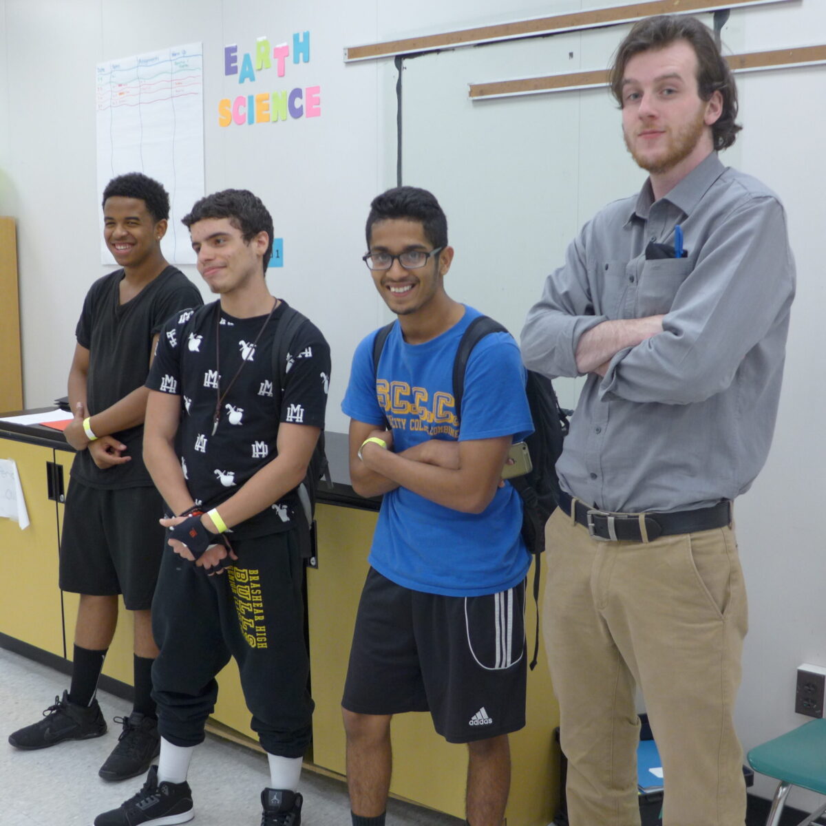 Three youth and an adult folding their arms and posing in a classroom
