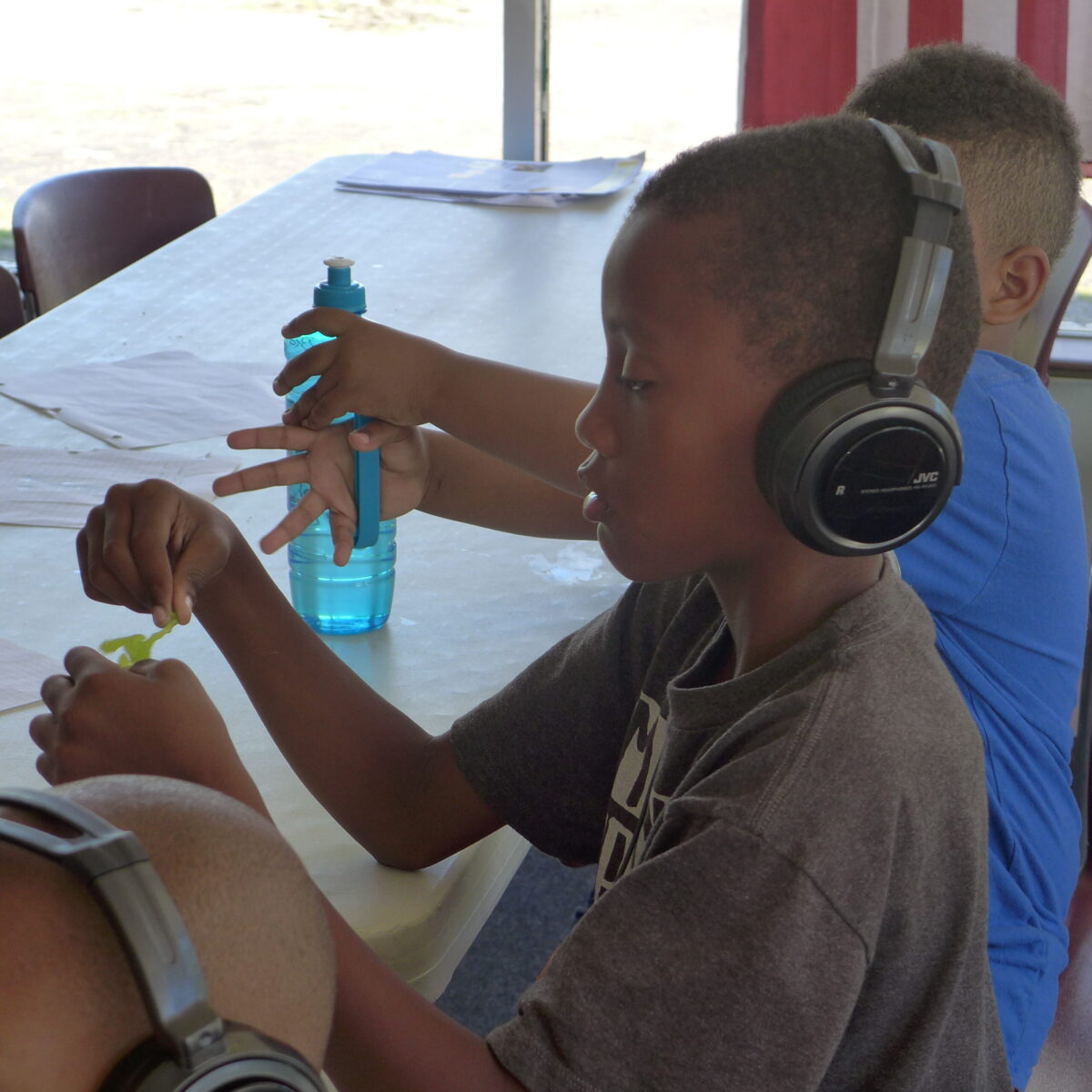 P1020698 Two youth, one wearing headphones, sitting at a white table