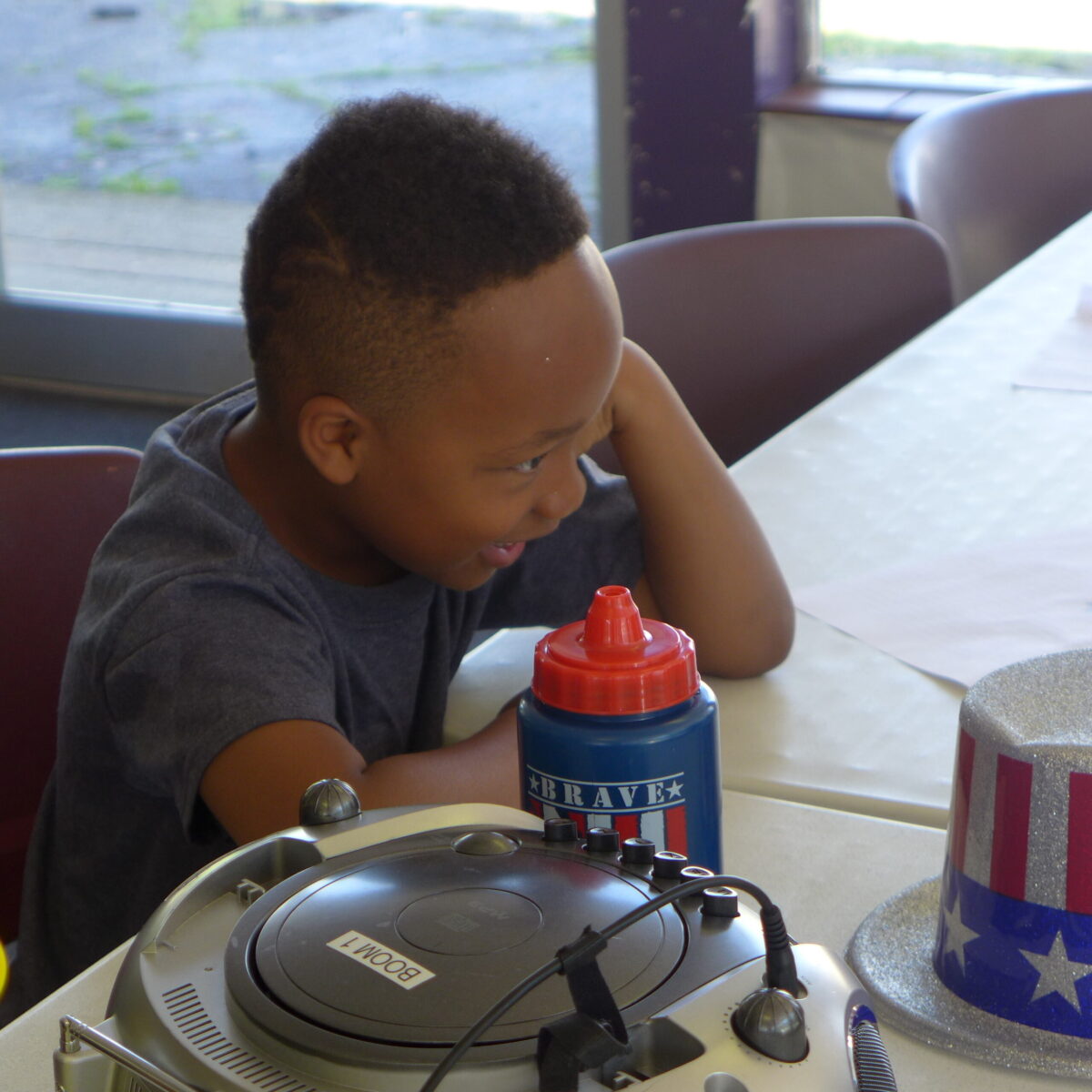 P1020699 A youth smiling sitting next to a water bottle on a white table