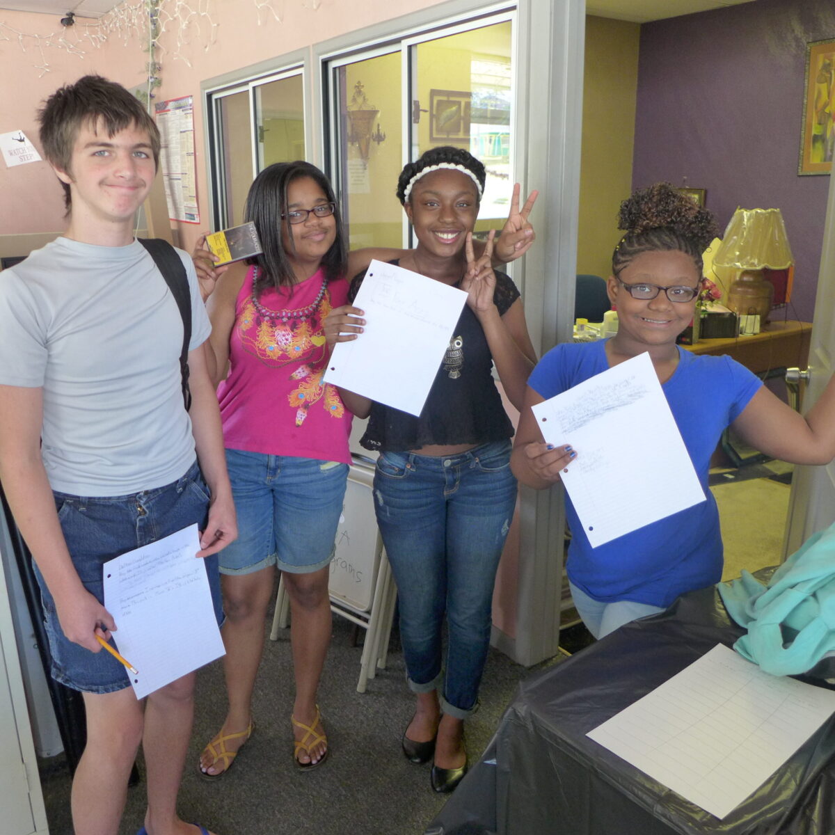 P1020700 Four youth smiling and holding up papers to the camera