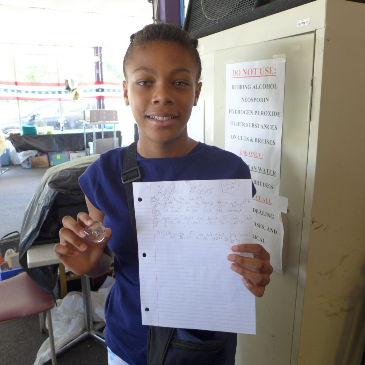 P1020701 A youth smiling and holding up a piece of paper in a classroom