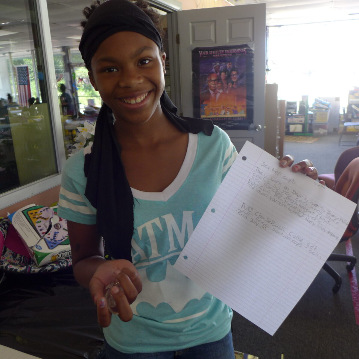 P1020702 A youth smiling and holding up a piece of paper in a classroom