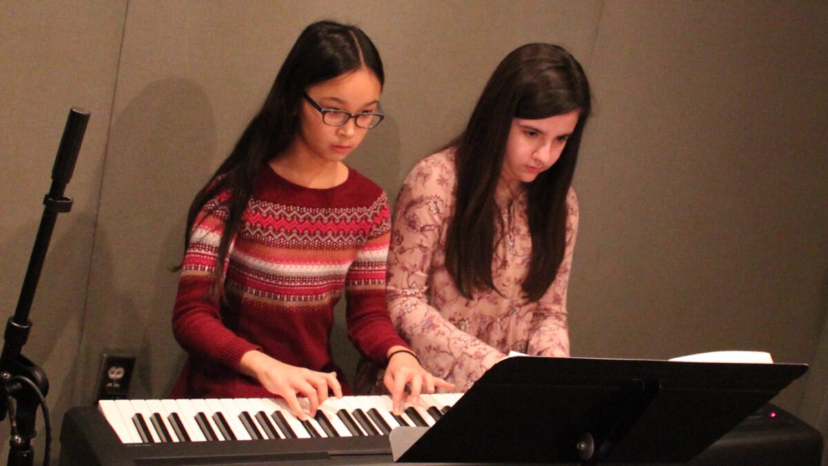 Two youth playing a piano keyboard in a radio studio