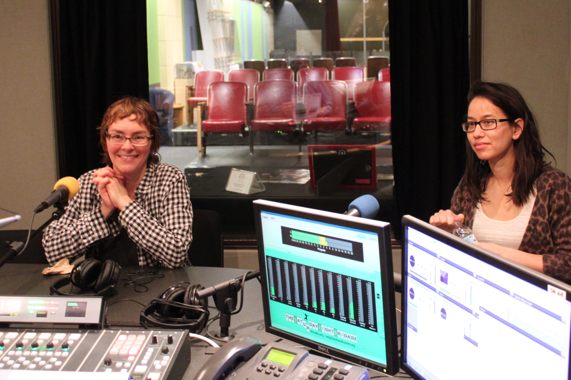Two adults sitting behind microphones being interviewed in a radio studio