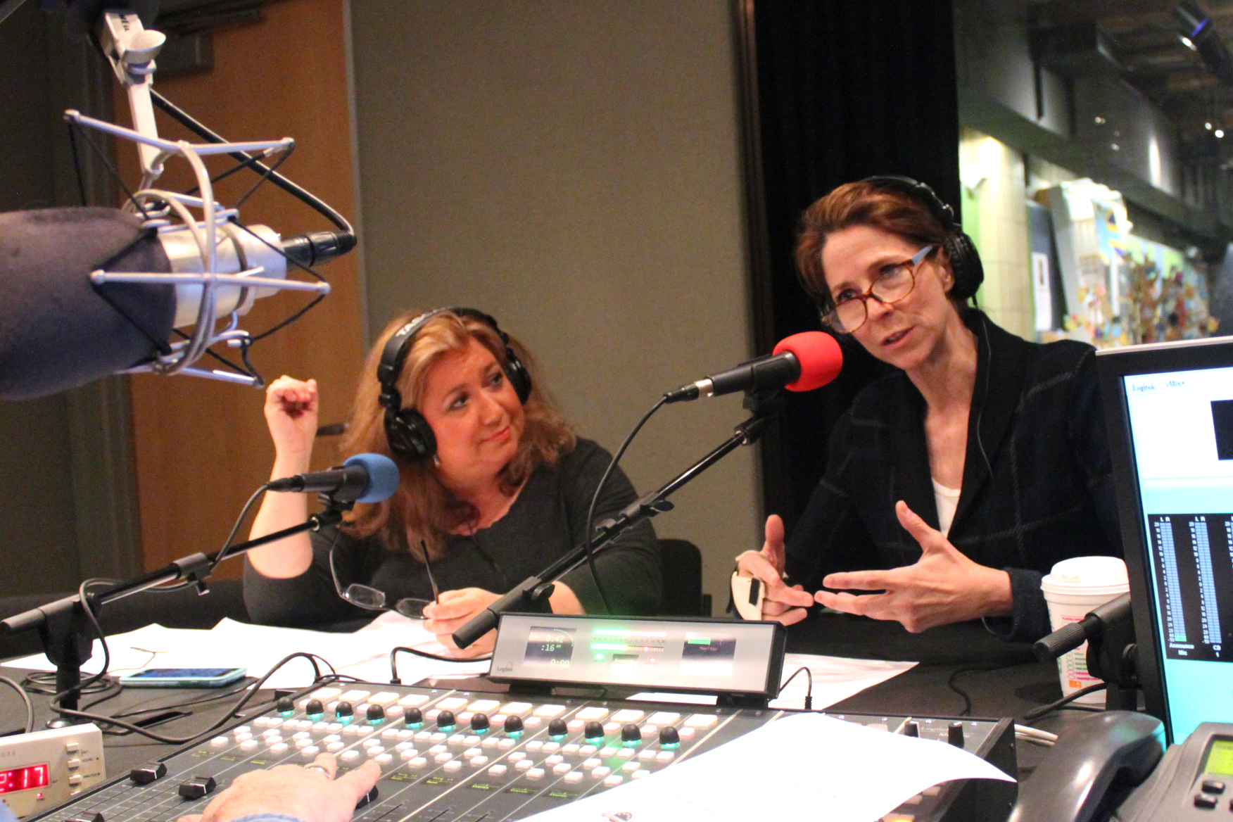 Two adults wearing headphones speaking into microphones being interviewed in a radio studio
