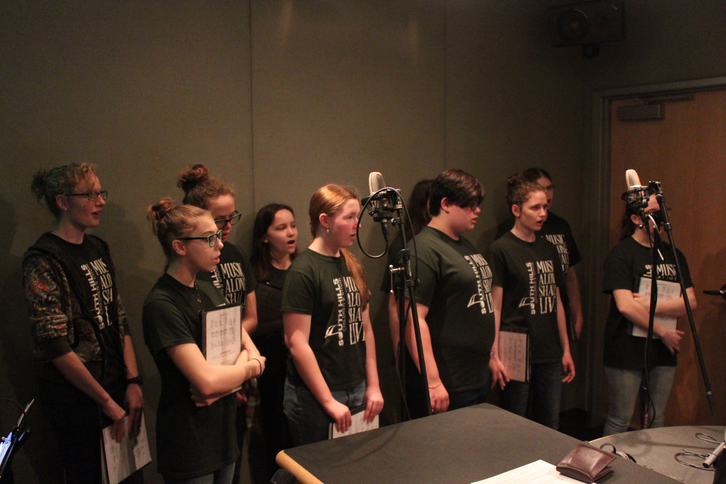 Ten teens singing in a choir in a radio studio