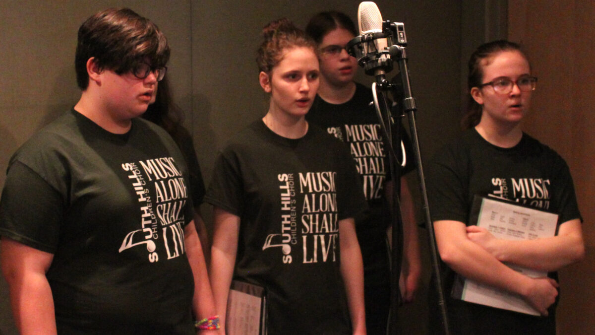 Four youth singing in a choir in a radio studio