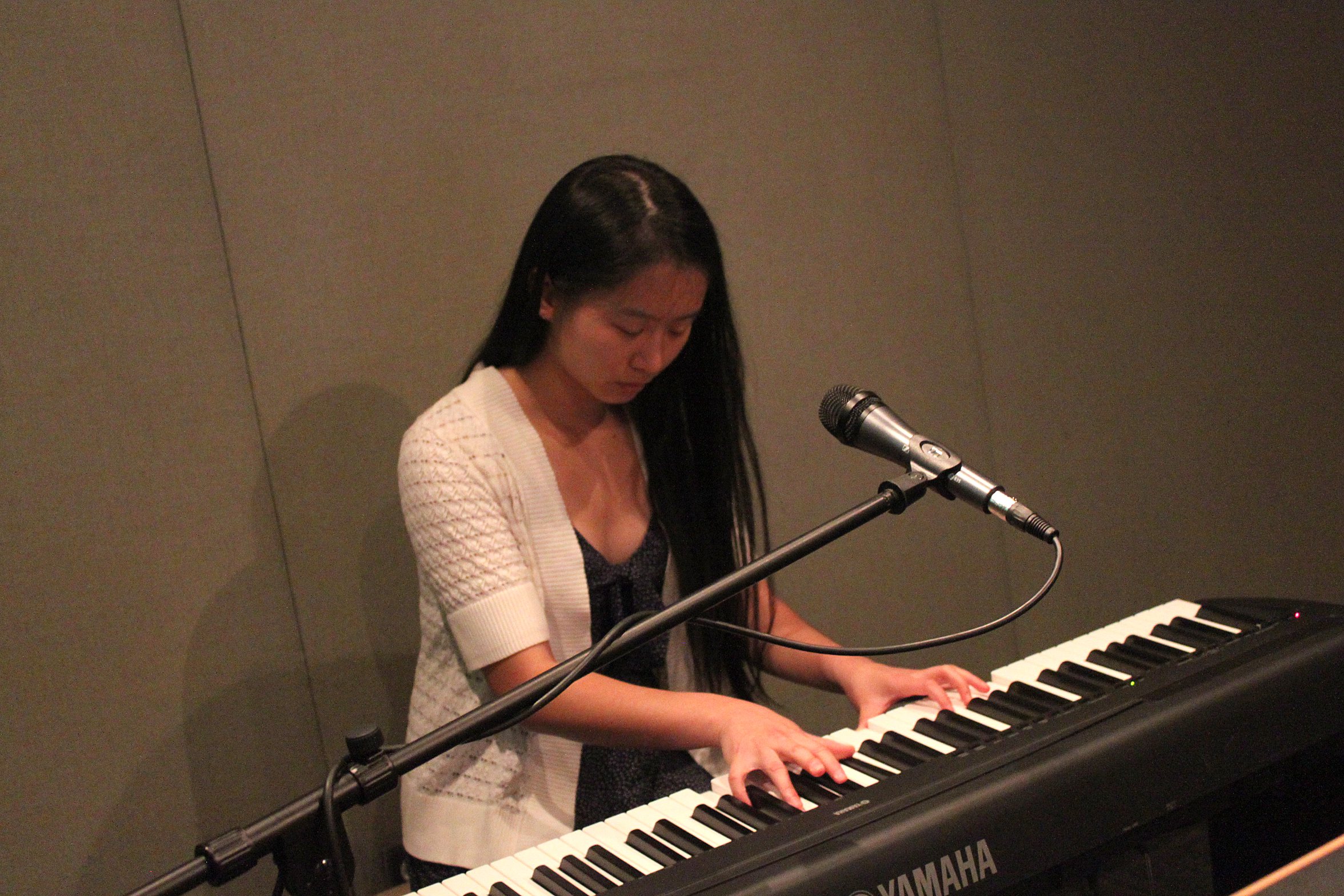 A teen playing piano keyboard sitting behind a microphone in a radio studio
