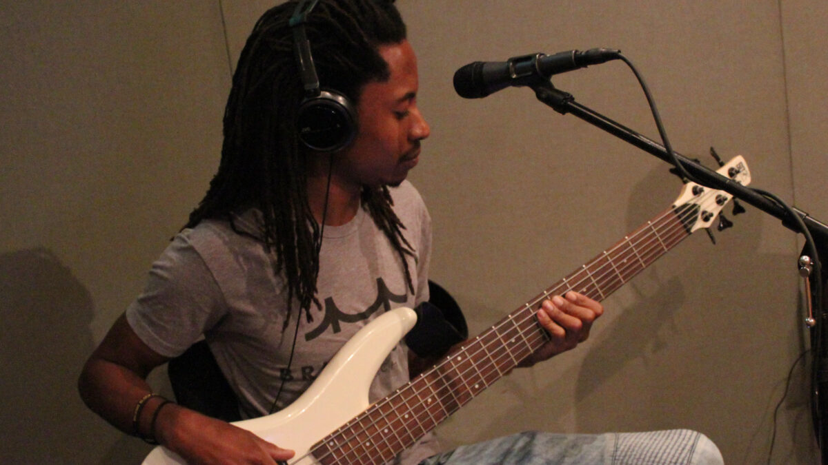 Teen wearing headphones and playing electric bass in a radio studio