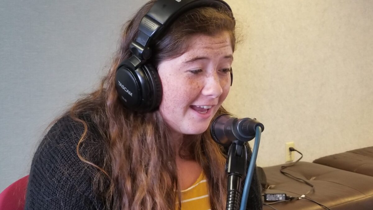 A teen wearing headphones and speaking into a microphone