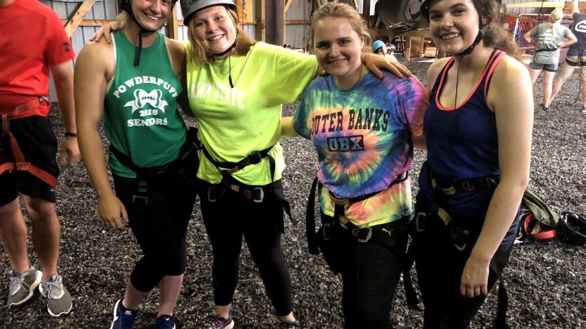 Four teens, three wearing helmets, smiling and posing in profile