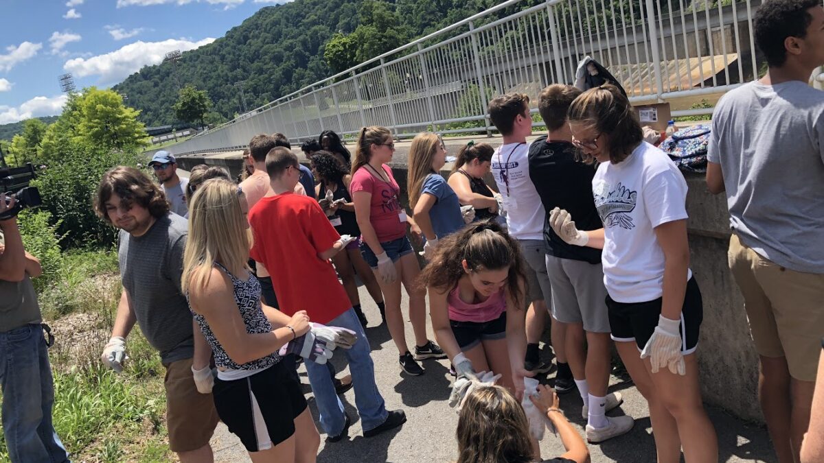 A crowd of young individuals wearing gloves and standing in front of a fence