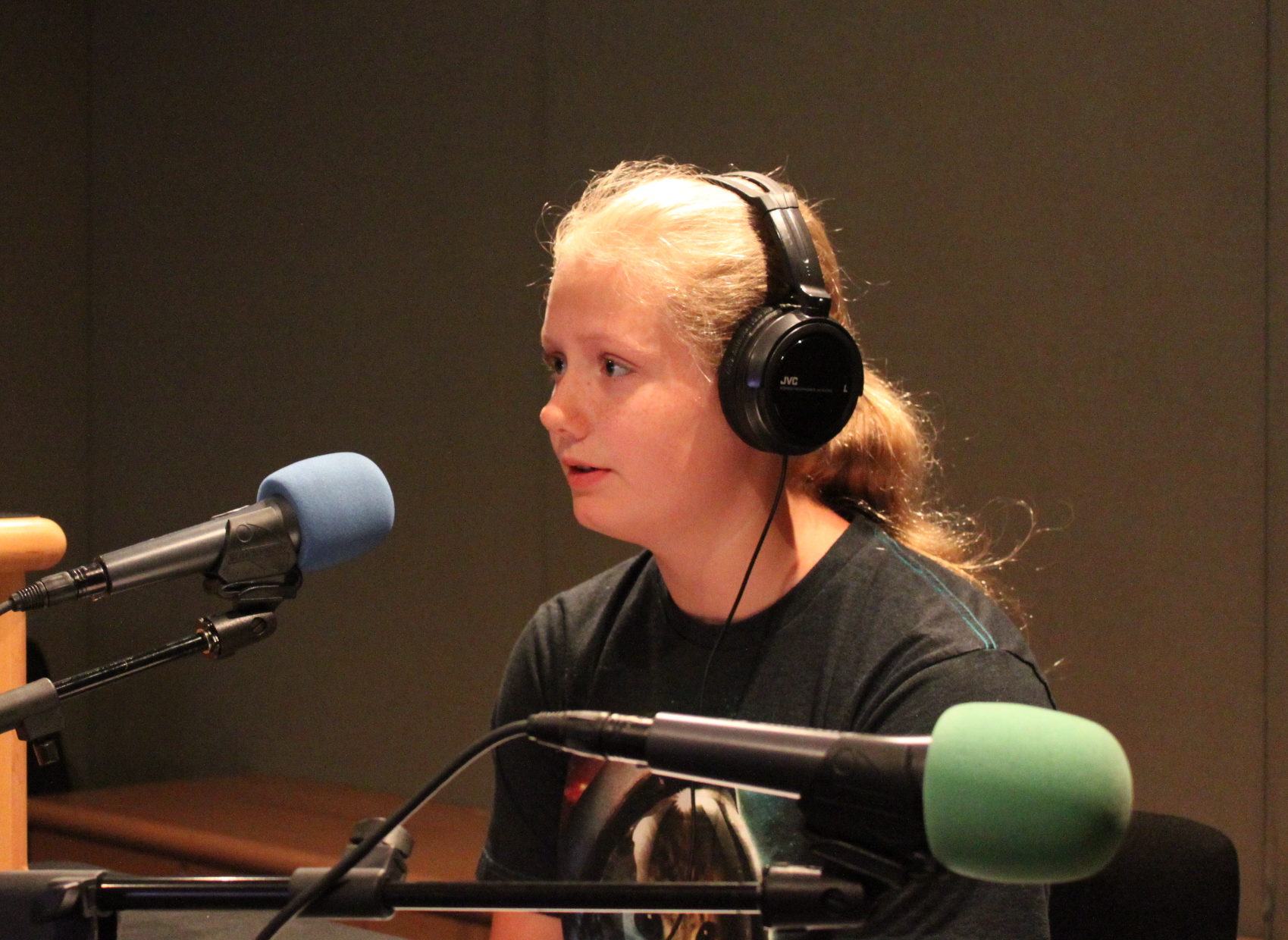 Teen wearing headphones speaking into a microphone in a radio studio